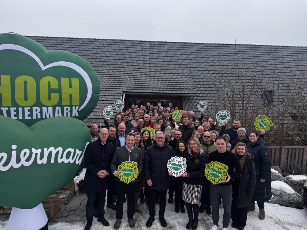 Eine Gruppe an Menschen posiert für ein Foto und hält Steiermark Schilder hoch.