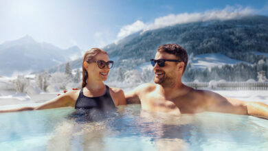 Glückliches Paar, das sich im Whirlpool im Freien im Ski Spa Resort entspannt. Winterurlaub.