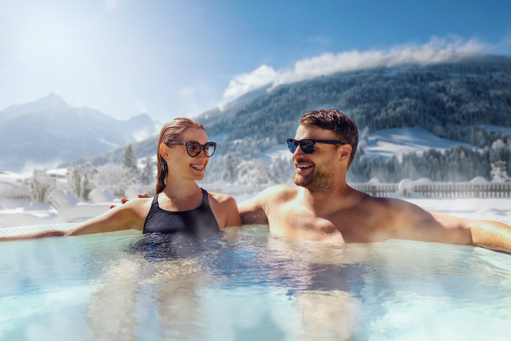 Glückliches Paar, das sich im Whirlpool im Freien im Ski Spa Resort entspannt. Winterurlaub.