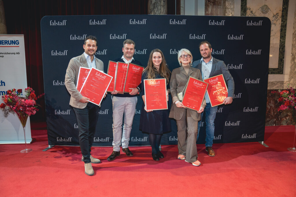 Eine Gruppe von fünf Personen posiert bei der Siegerehrung für ein Bild. Sie halten rote Urkunden in der Hand. 