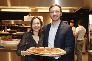 Zwei Personen halten eine Pizza und lächeln.